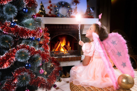 little fairy girl with magic wand near a Christmas tree, firepla
